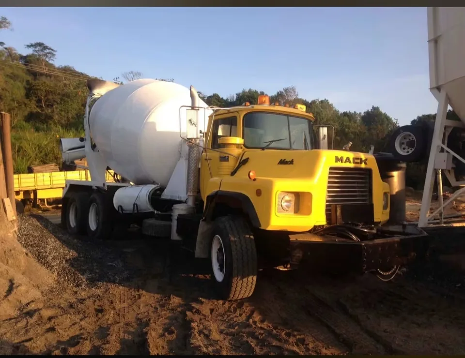 Camion mixer Mack amarillo cargando concreto junto al silo de una planta
